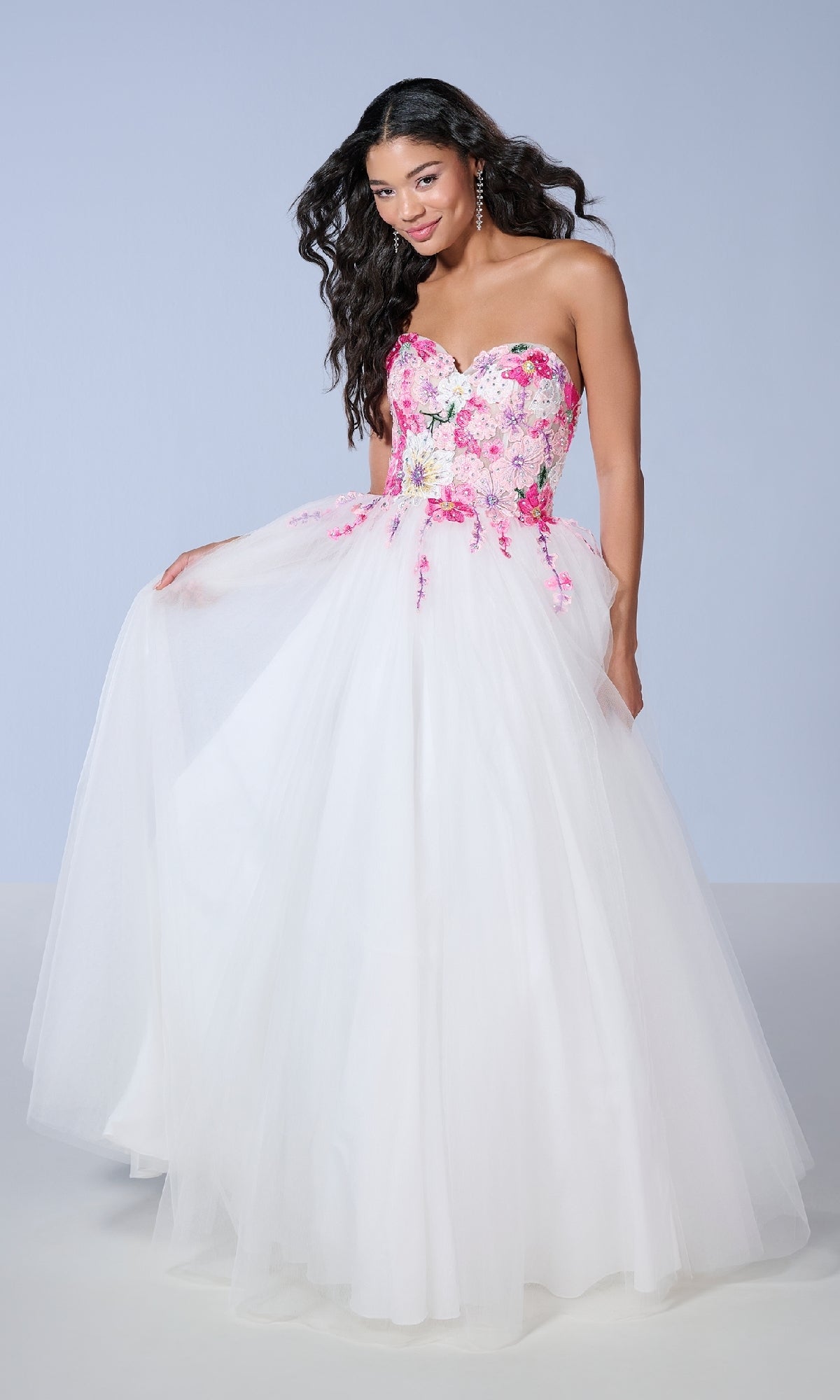 A woman models the Tiffany 16142, a long prom dress featuring a strapless tulle silhouette with a sheer corset bodice and pink and purple floral lace embroidery, set against a simple light background.